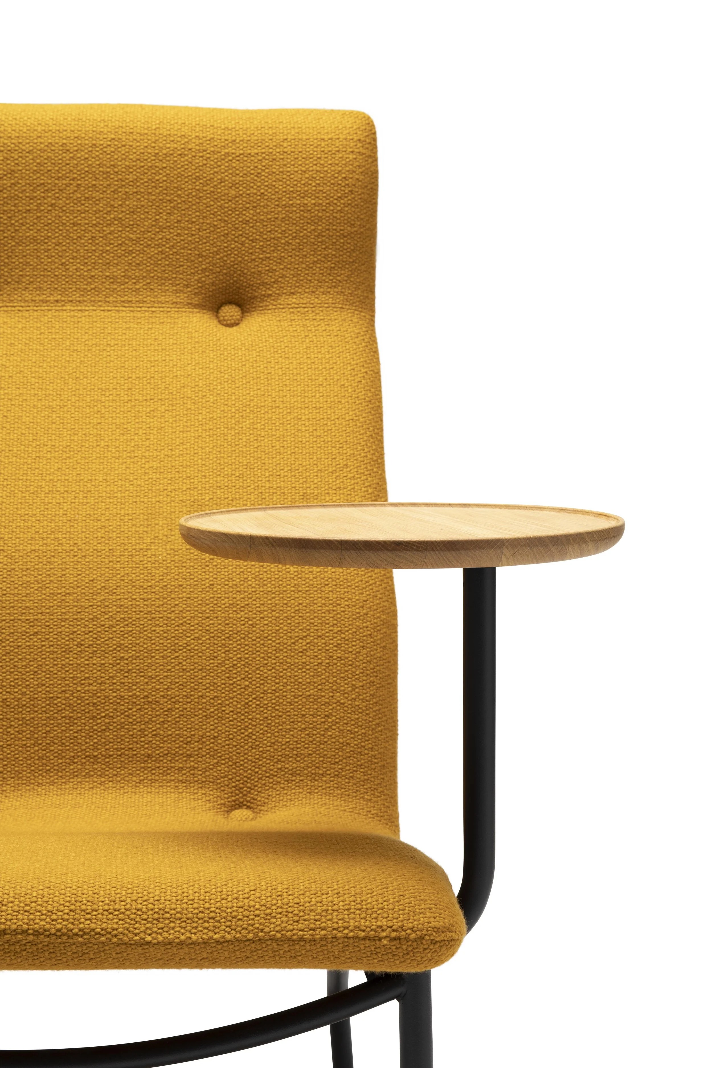 Close-up of a modern yellow upholstered chair with a small wooden side table attached to its armrest.