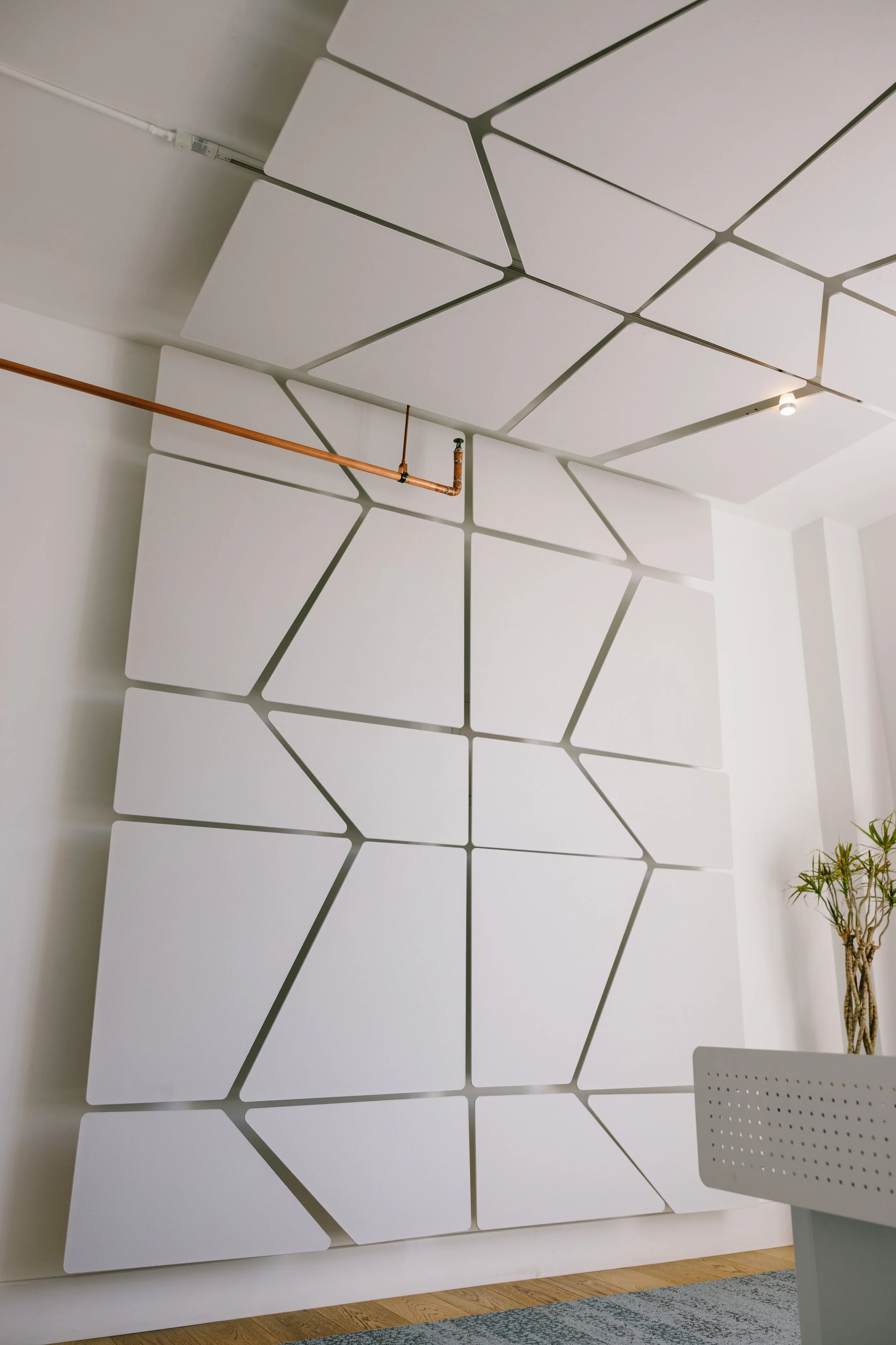 Modern white acoustic wall panels by Snowsound, with angular geometric design in an office or conference room.