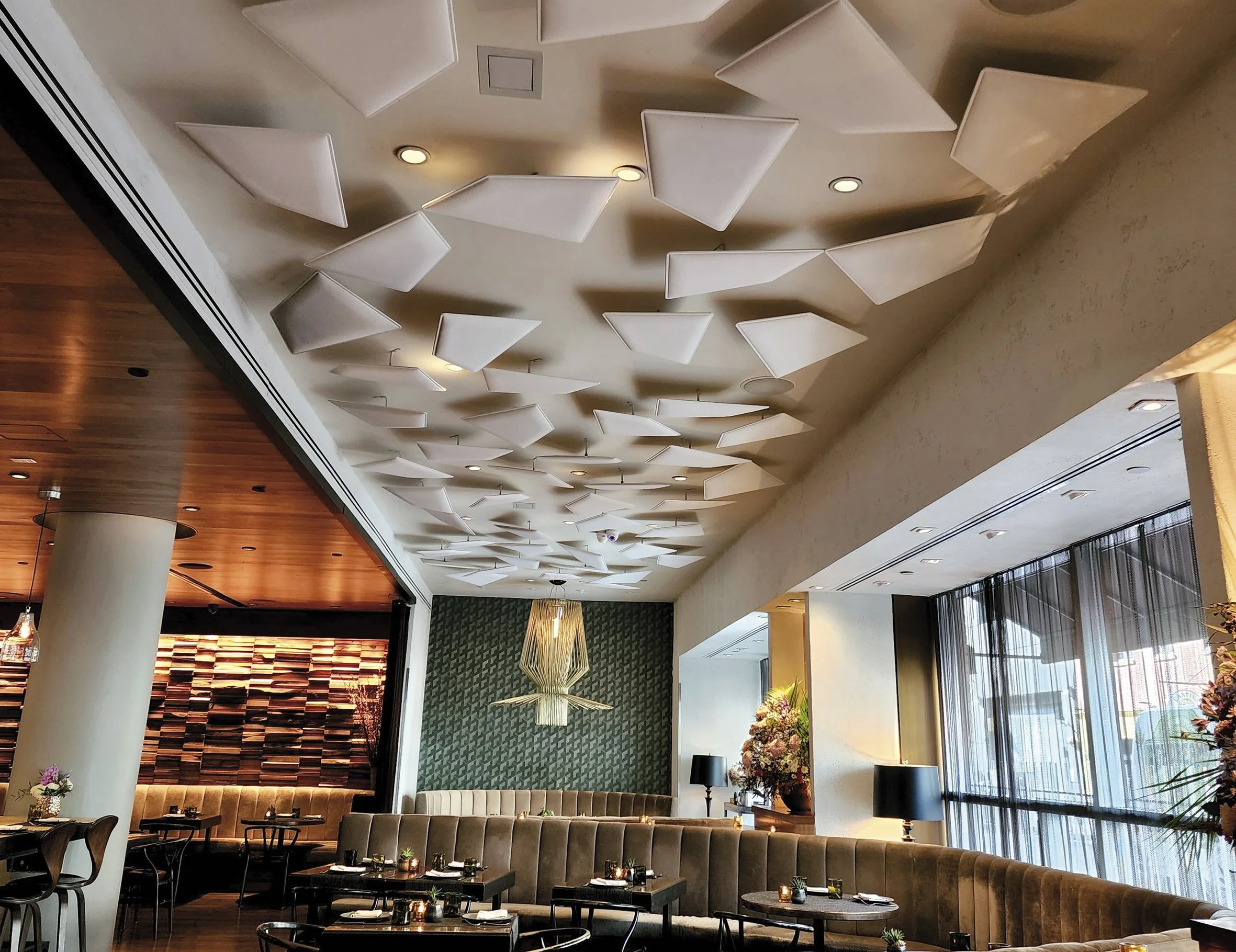 Modern restaurant interior with geometric acoustic ceiling panels from Snowsound designed to reduce noise and enhance sound quality.