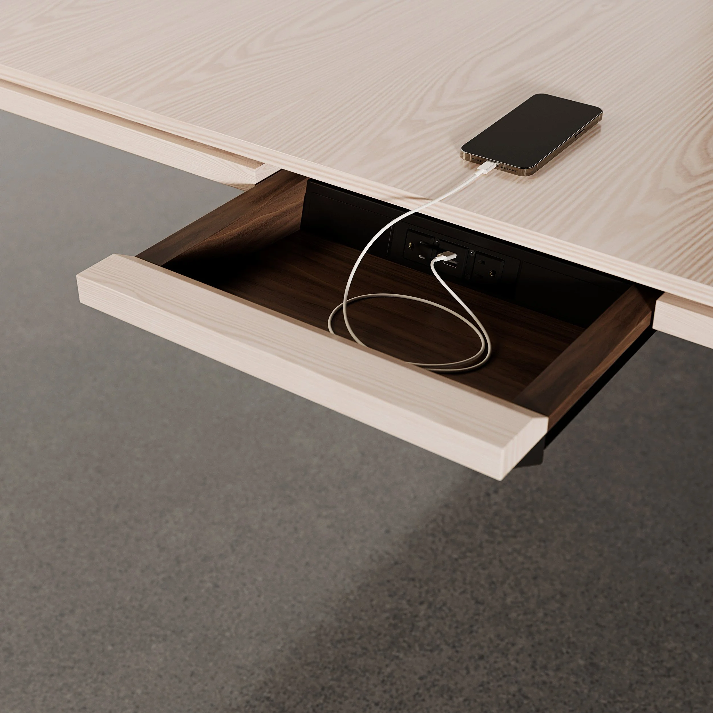 Open desk drawer from Halcon with built-in charging port and a smartphone plugged in, showcasing technology-friendly office furniture.