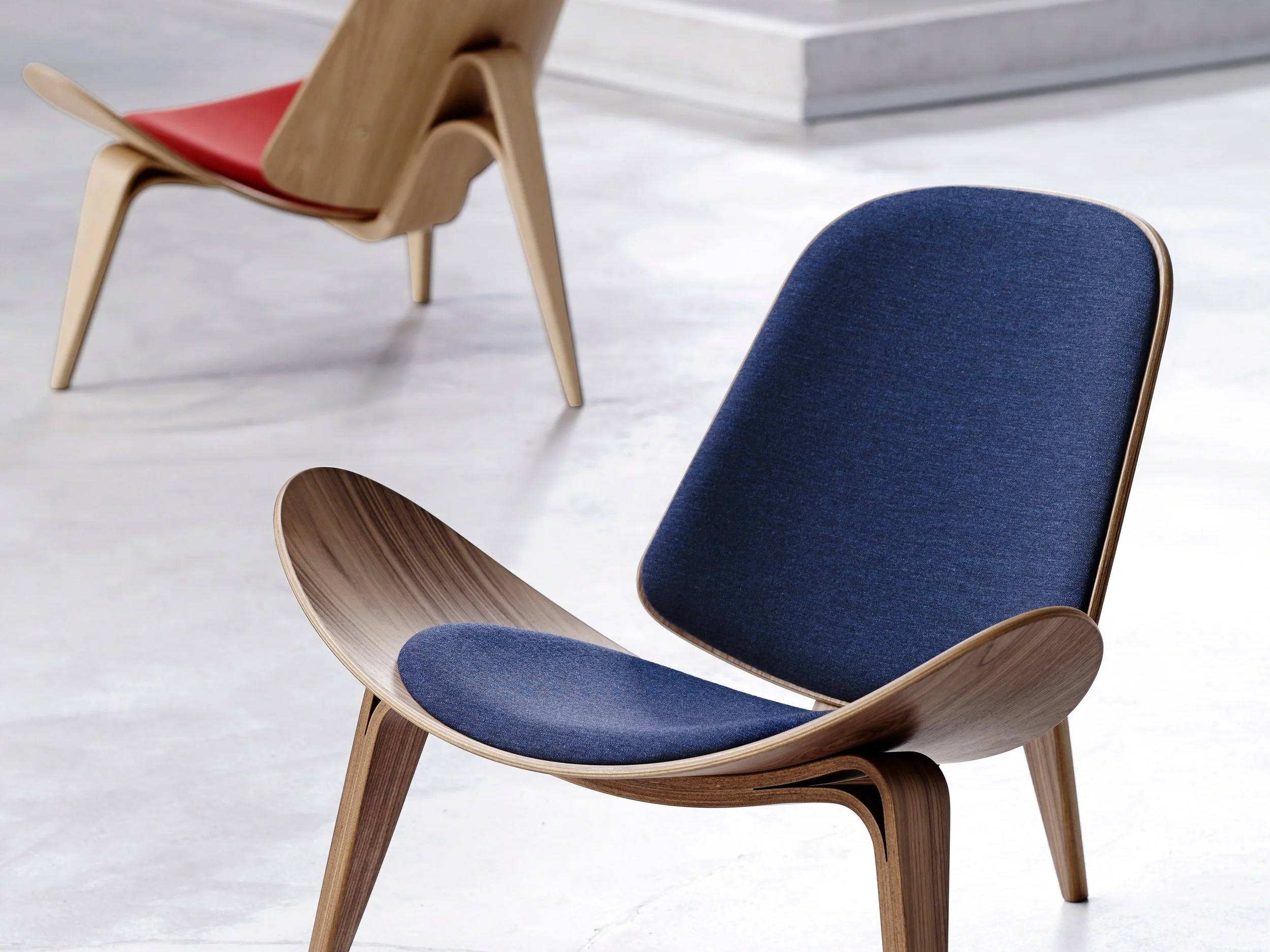 Modern wooden Carl Hansen & Søn chair with curved dark blue upholstered seat and backrest, featuring matching wooden armrests and legs.