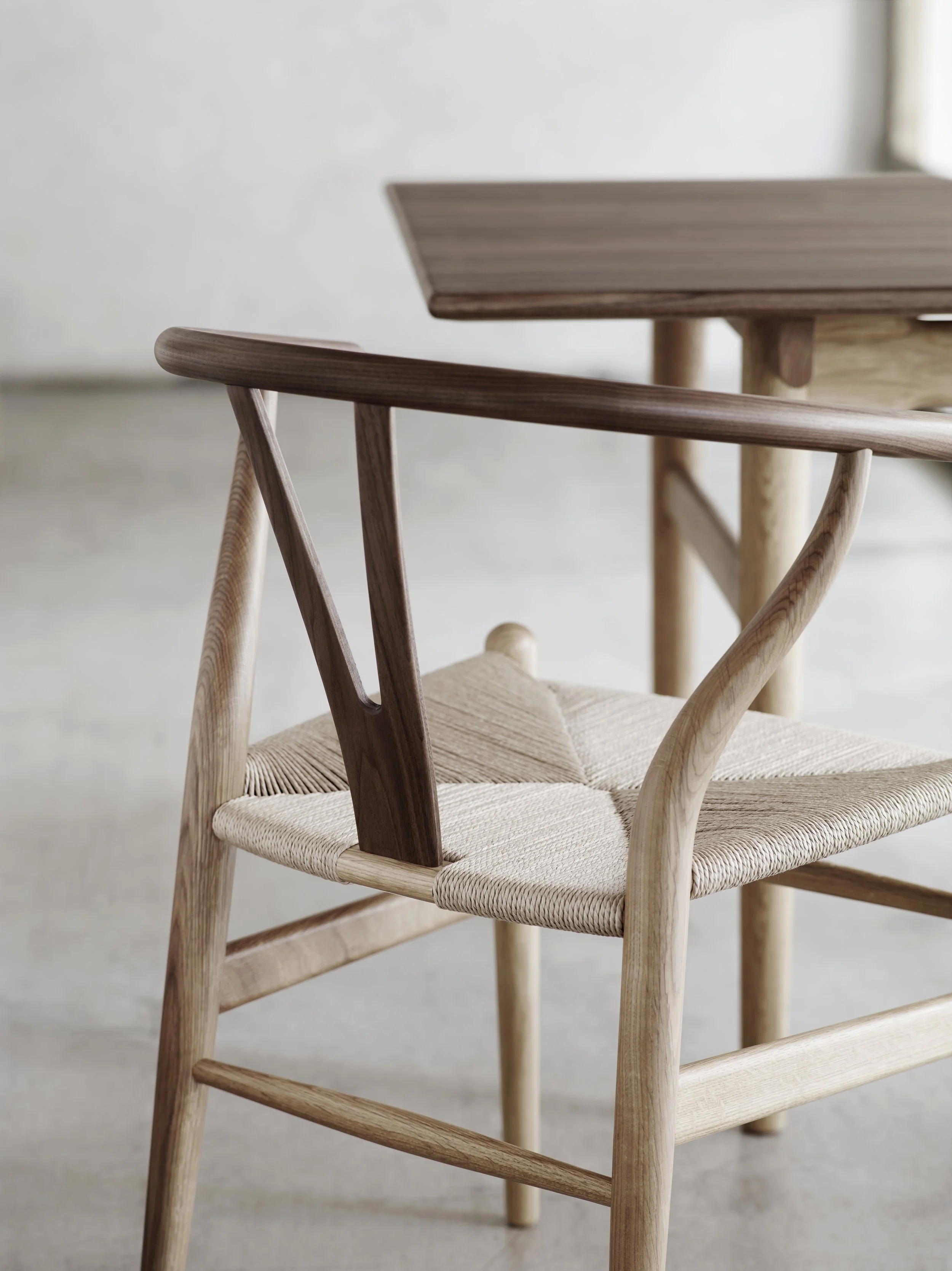 Close-up of a modern wooden chair by Carl Hansen & Søn with a light woven seat and contrasting dark and light wooden backrest.
