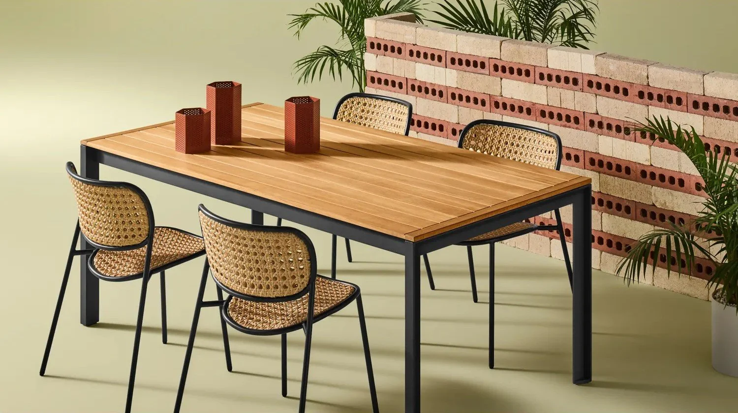 A wooden dining table with black metal legs surrounded by four woven cane chairs from Blu Dot.