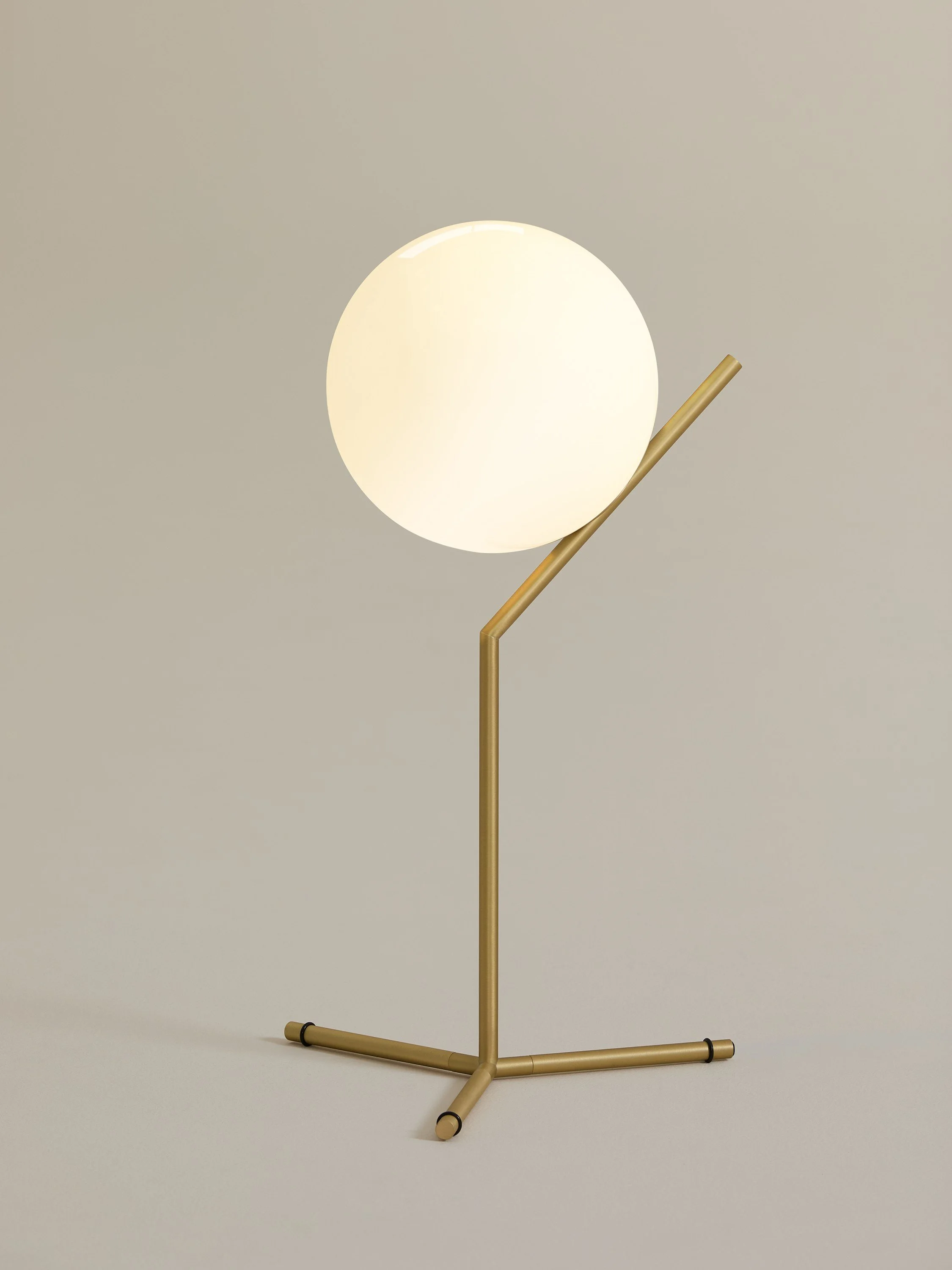 Modern spherical floor lamp with gold metal stand by FLOS.