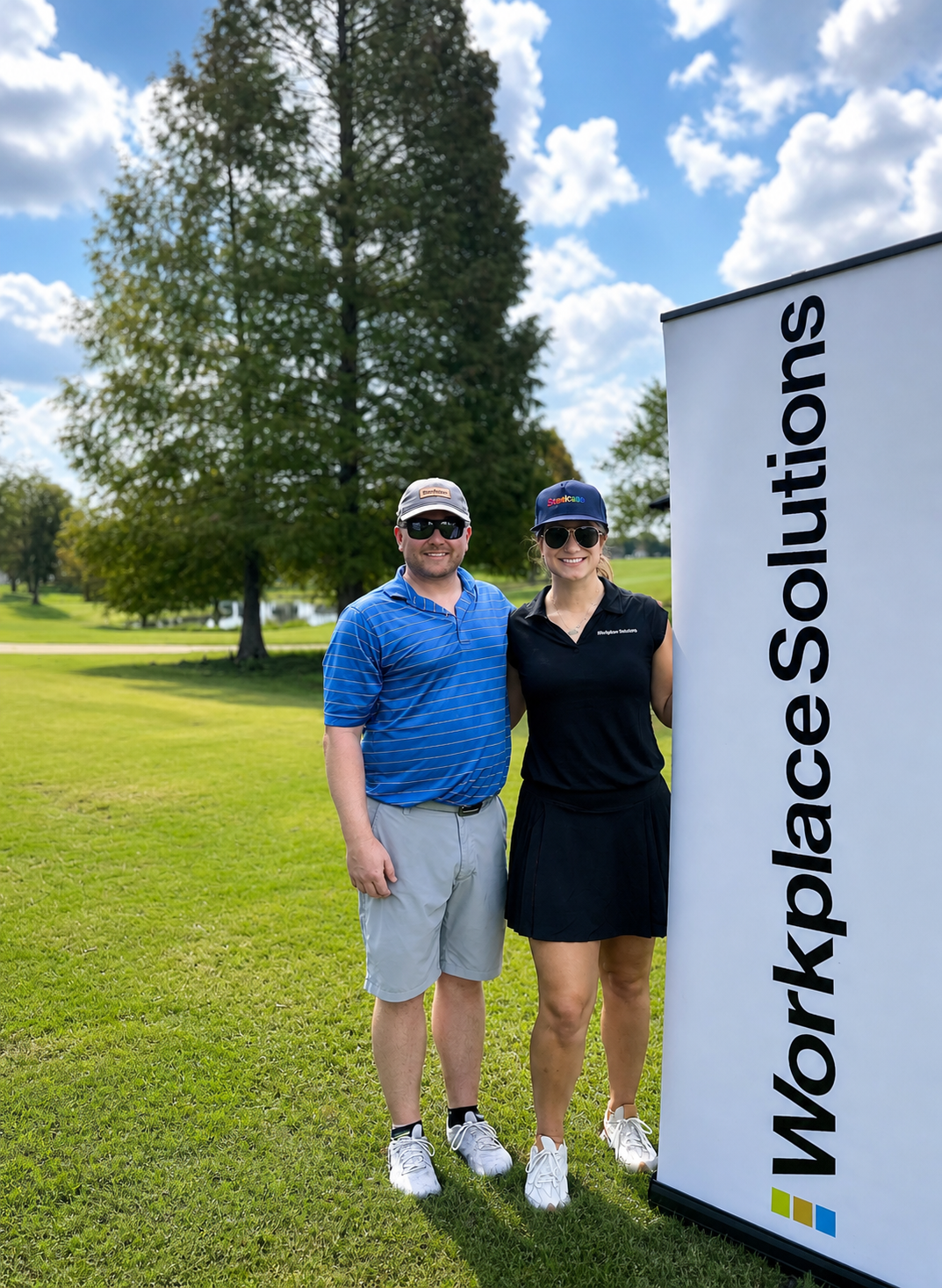 Members of the Workplace Solutions and Steelcase team standing outdoors on a golf course, smiling for a photo.