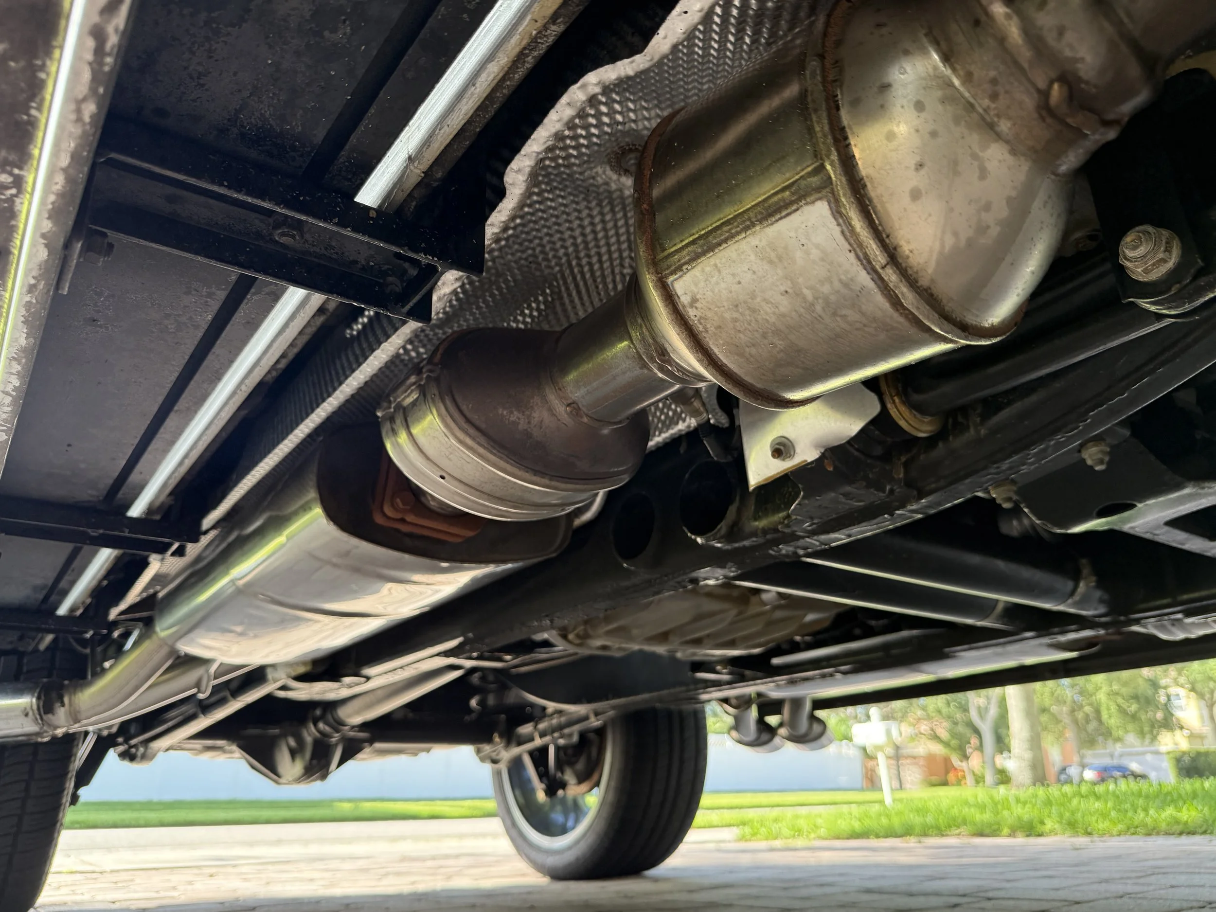 Underneath view of a car showing its exhaust system including the catalytic converter and muffler.