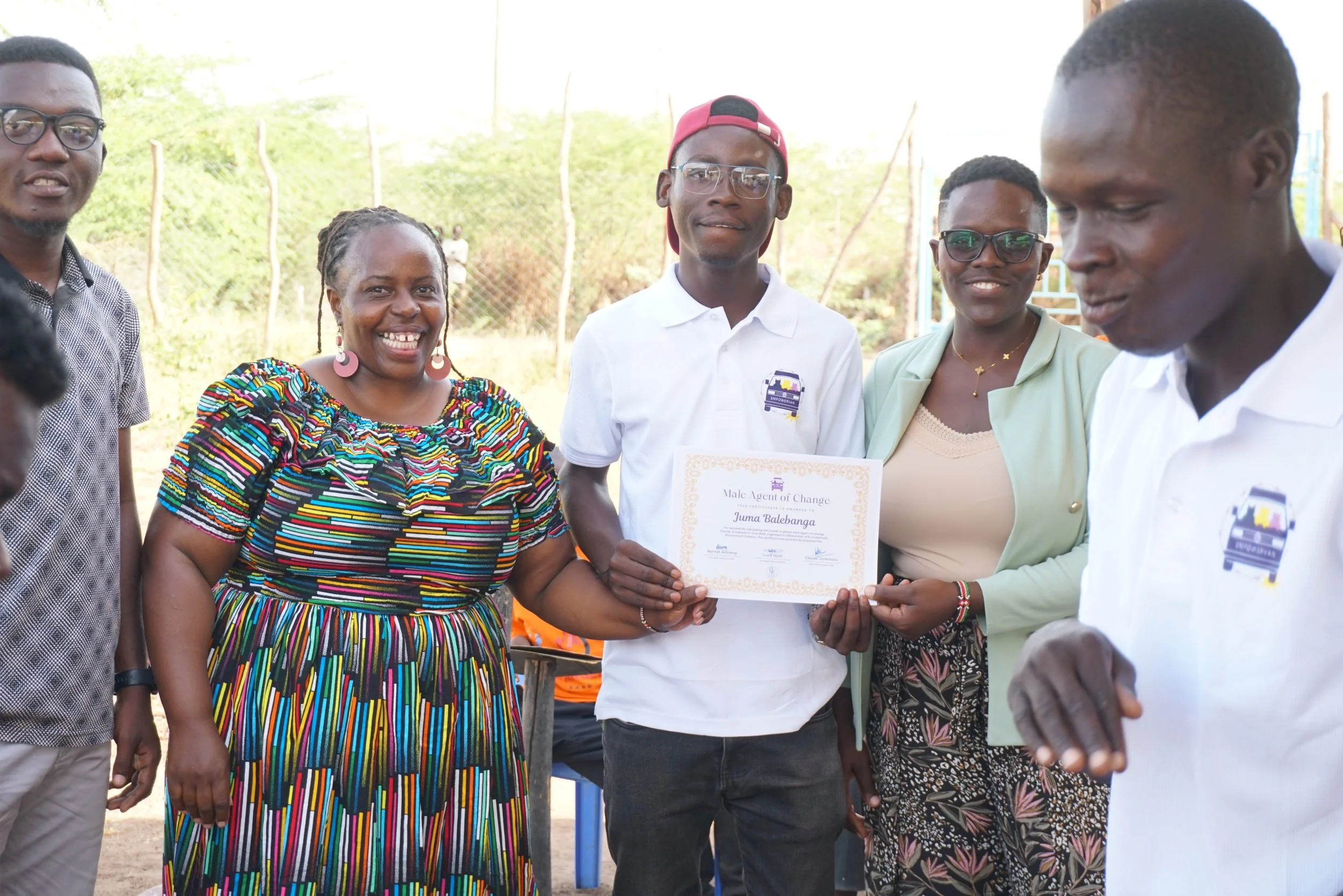 Juma with his Empoervan Certification and Empowervan standing next to EmpowerVan members.