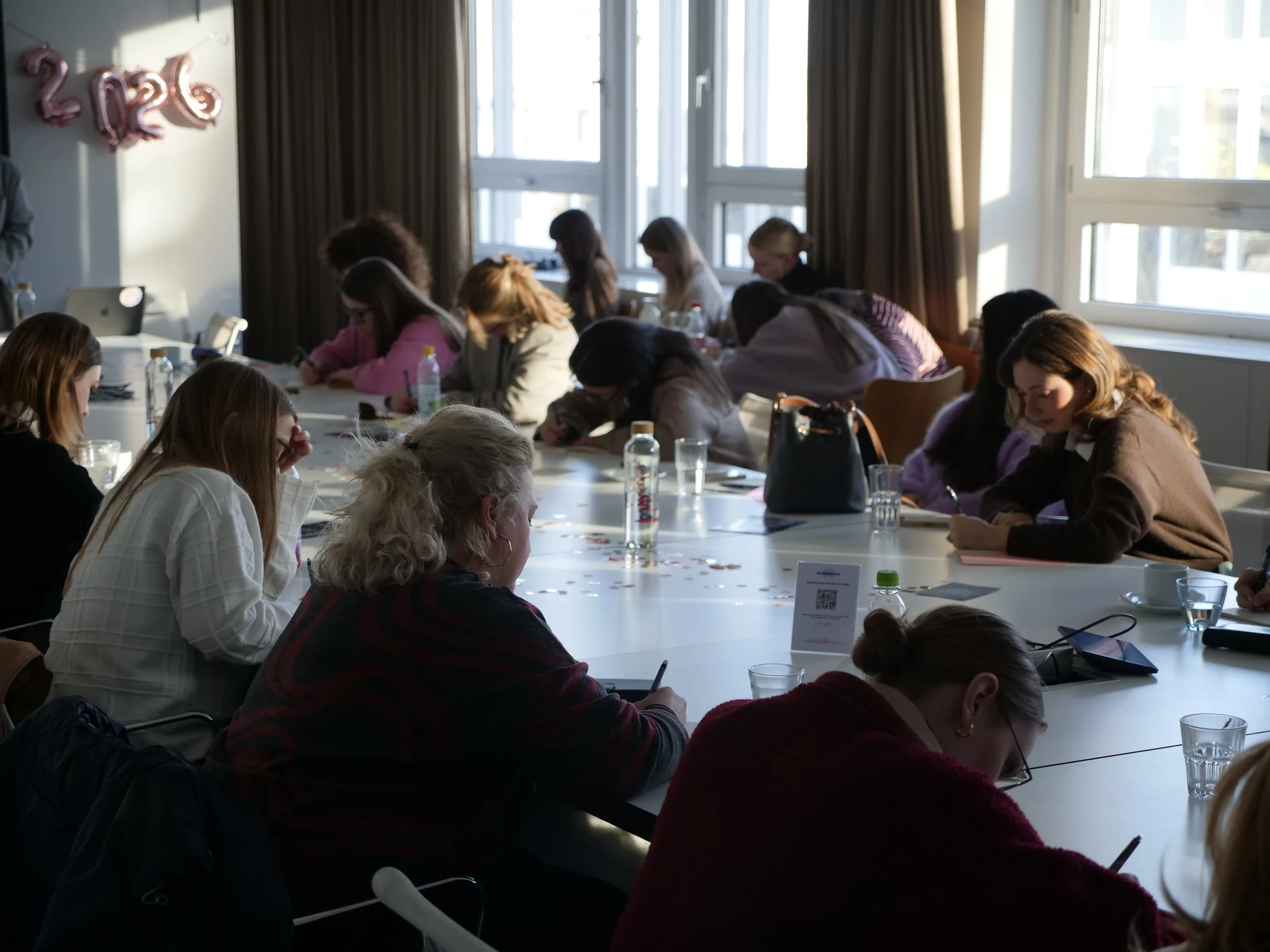 Ein Team sitzt am Tisch und schreibt in Journals
