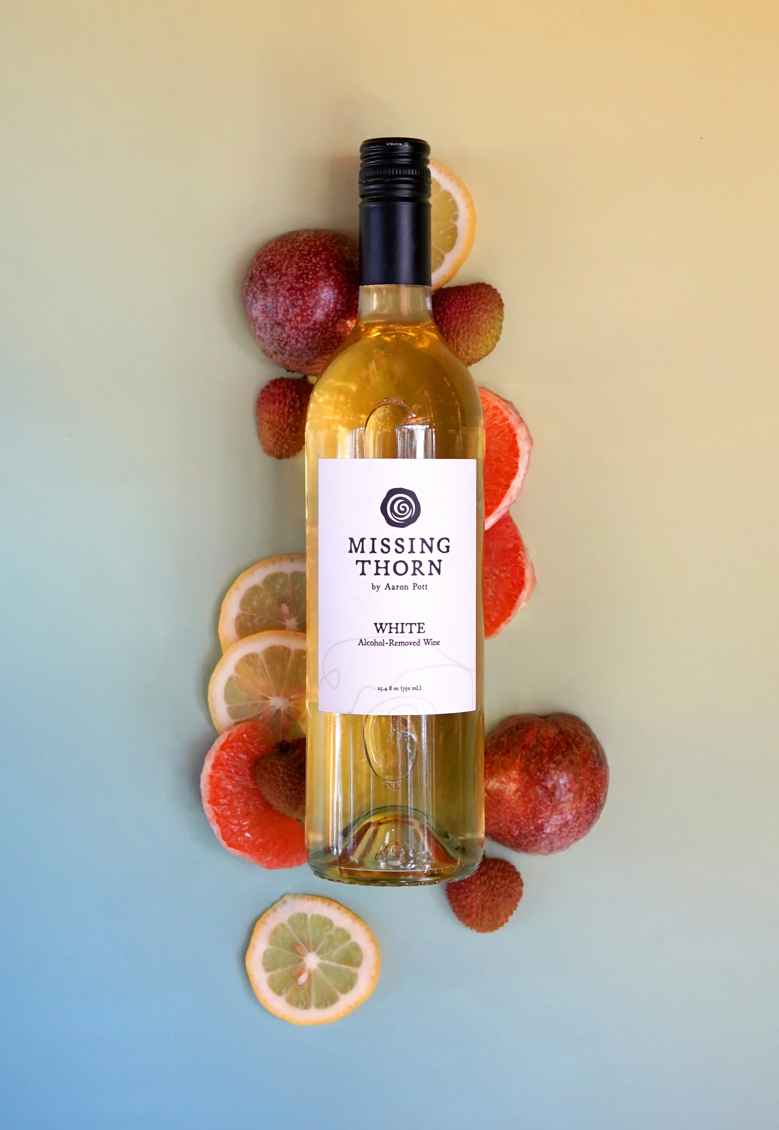 A bottle of wine labeled 'Missing Thorn' surrounded by slices of lemon, grapefruit, lychee, and whole lychee on a gradient background.