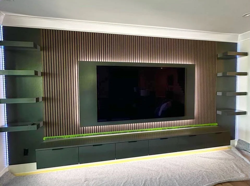 Custom entertainment wall with vertical wood slats, floating TV cabinet and LED illuminated shelves in Charlotte NC