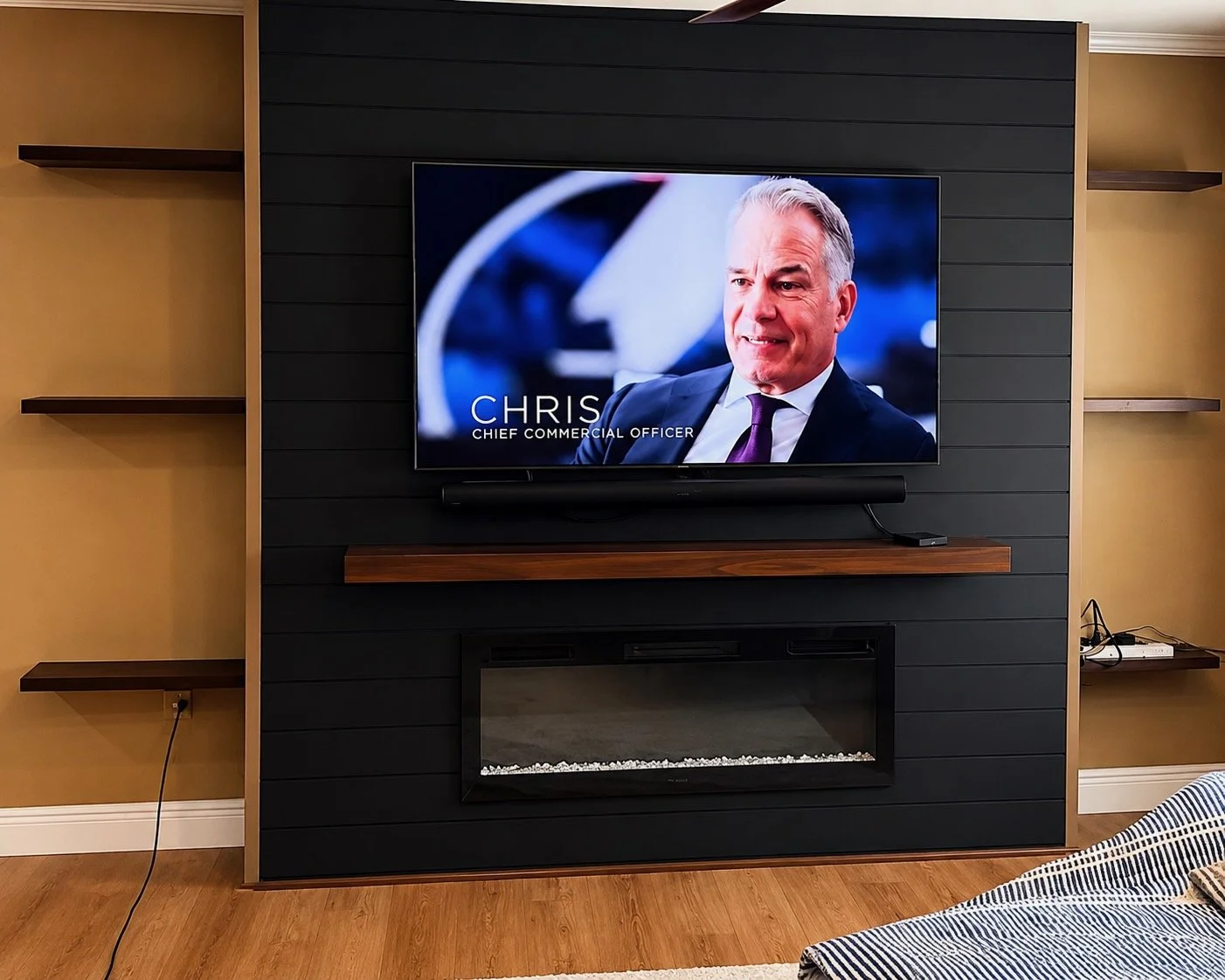 Modern fireplace media wall with black shiplap panels and floating shelves in Florida