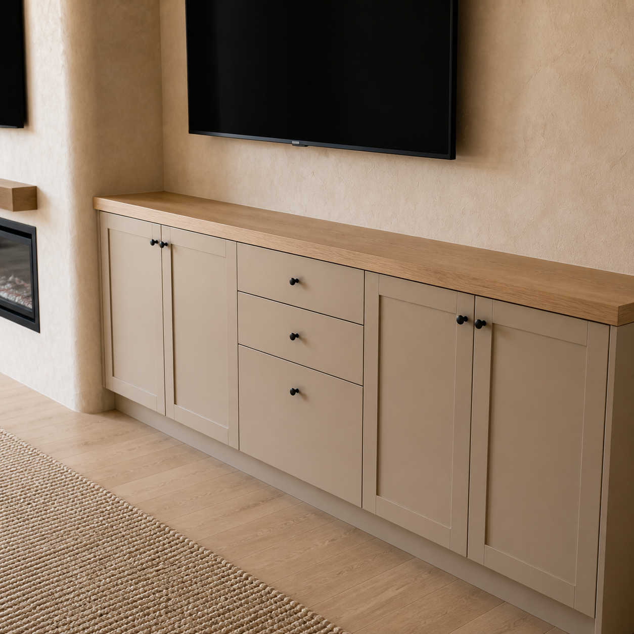 Greige closed storage cabinets with an oak countertop integrated into a limewash entertainment wall