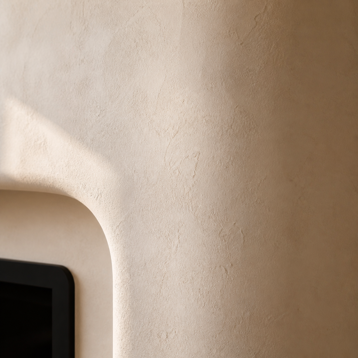 Close-up of a warm cream textured plaster finish with a softly rounded Mediterranean fireplace surround