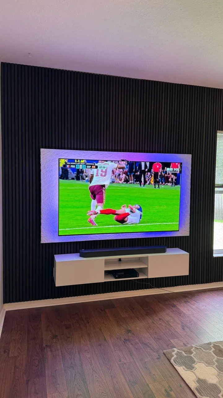 Modern black slat media wall with floating white cabinet, textured TV surround, and concealed wiring completed in Tampa, Florida.