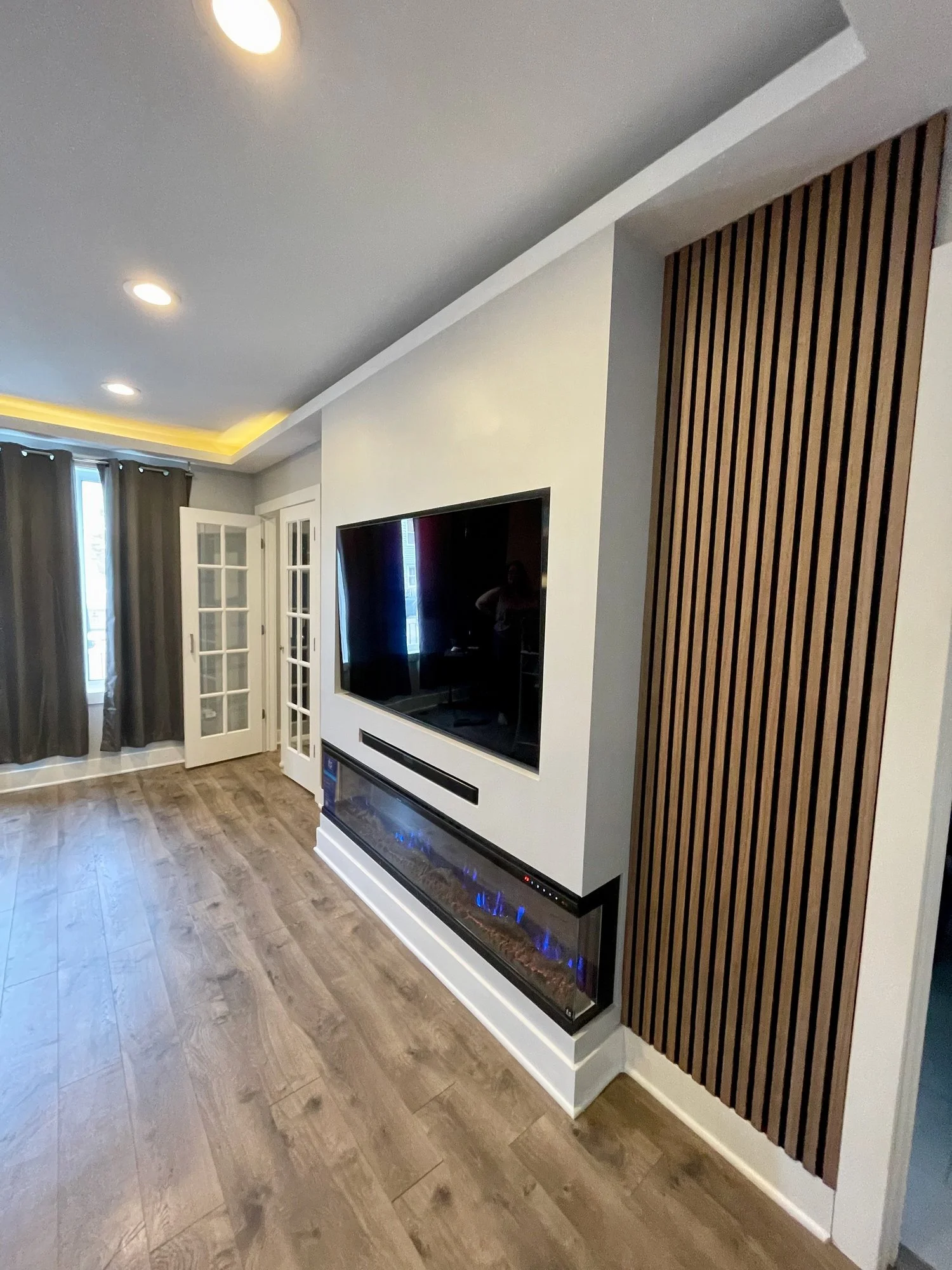 The electric fireplace offers multi-angle visibility and enhances the sleek, minimalist design of the painted entertainment wall.