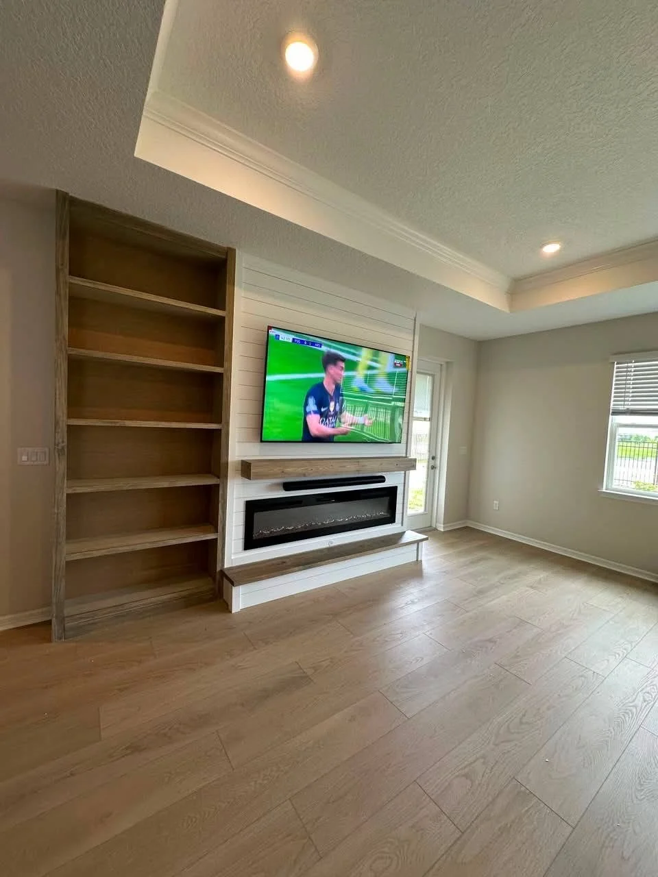 Wide-angle view of a modern entertainment center with shiplap feature wall and built-in shelving