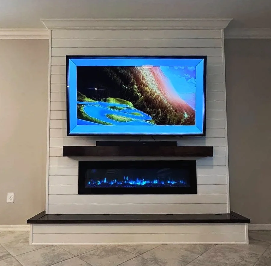 Front view of a custom shiplap fireplace wall in Houston with integrated electric fireplace, television, crown molding, and dark stained wood accents.