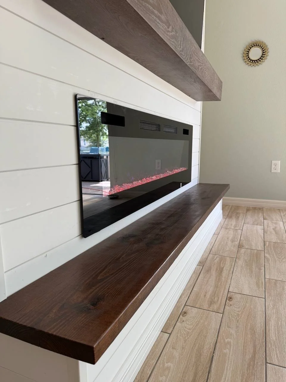 Detailed view of the lower portion of the media wall showing the solid wood bench and clean shiplap paneling with an inset electric fireplace.