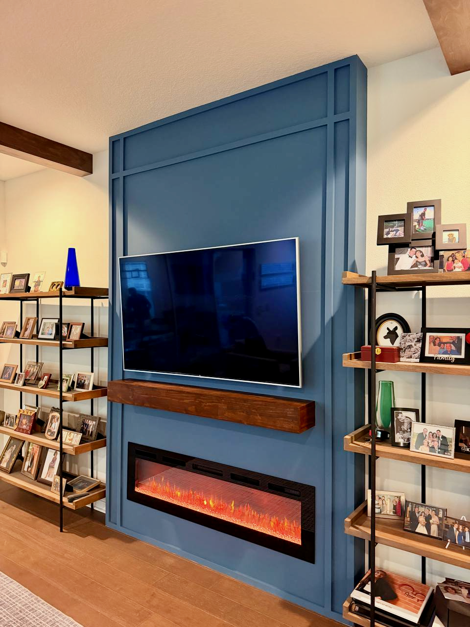 Modern blue fireplace media wall with wood mantel and integrated electric fireplace in Orlando Florida