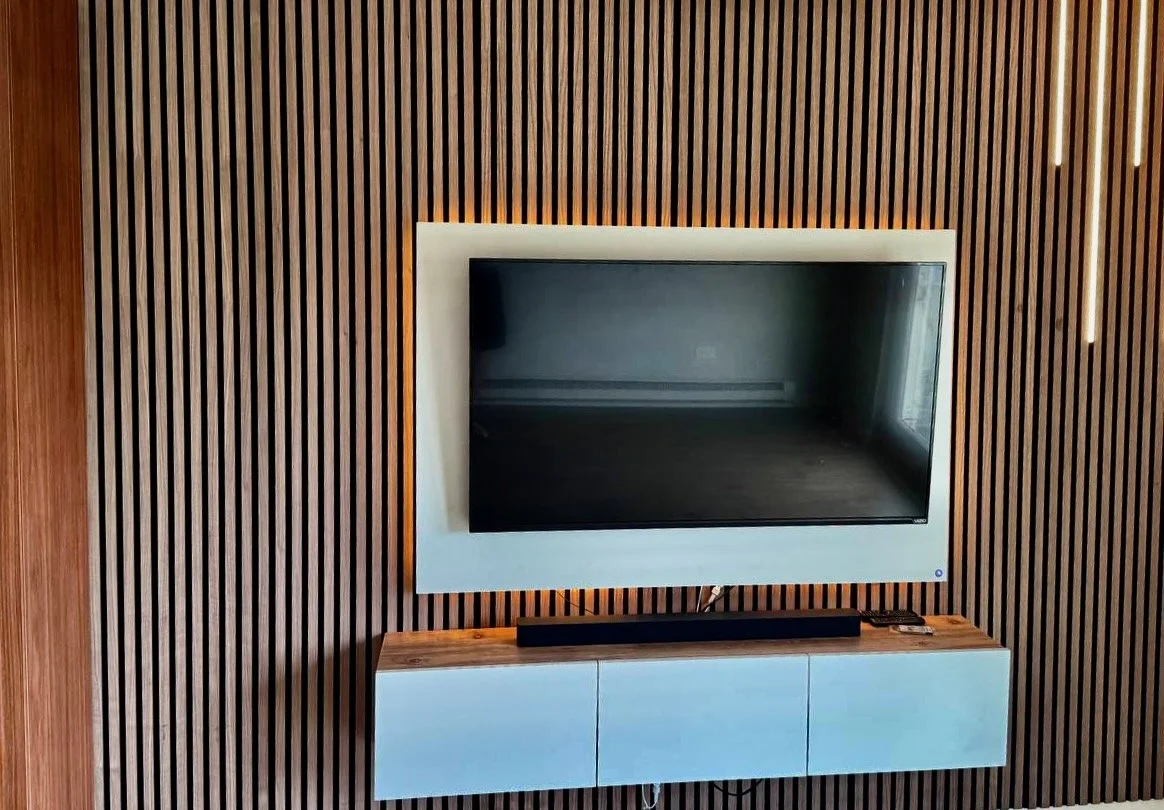 Close-up of Orlando built-in entertainment center featuring backlit TV panel and contemporary wood slat cladding.