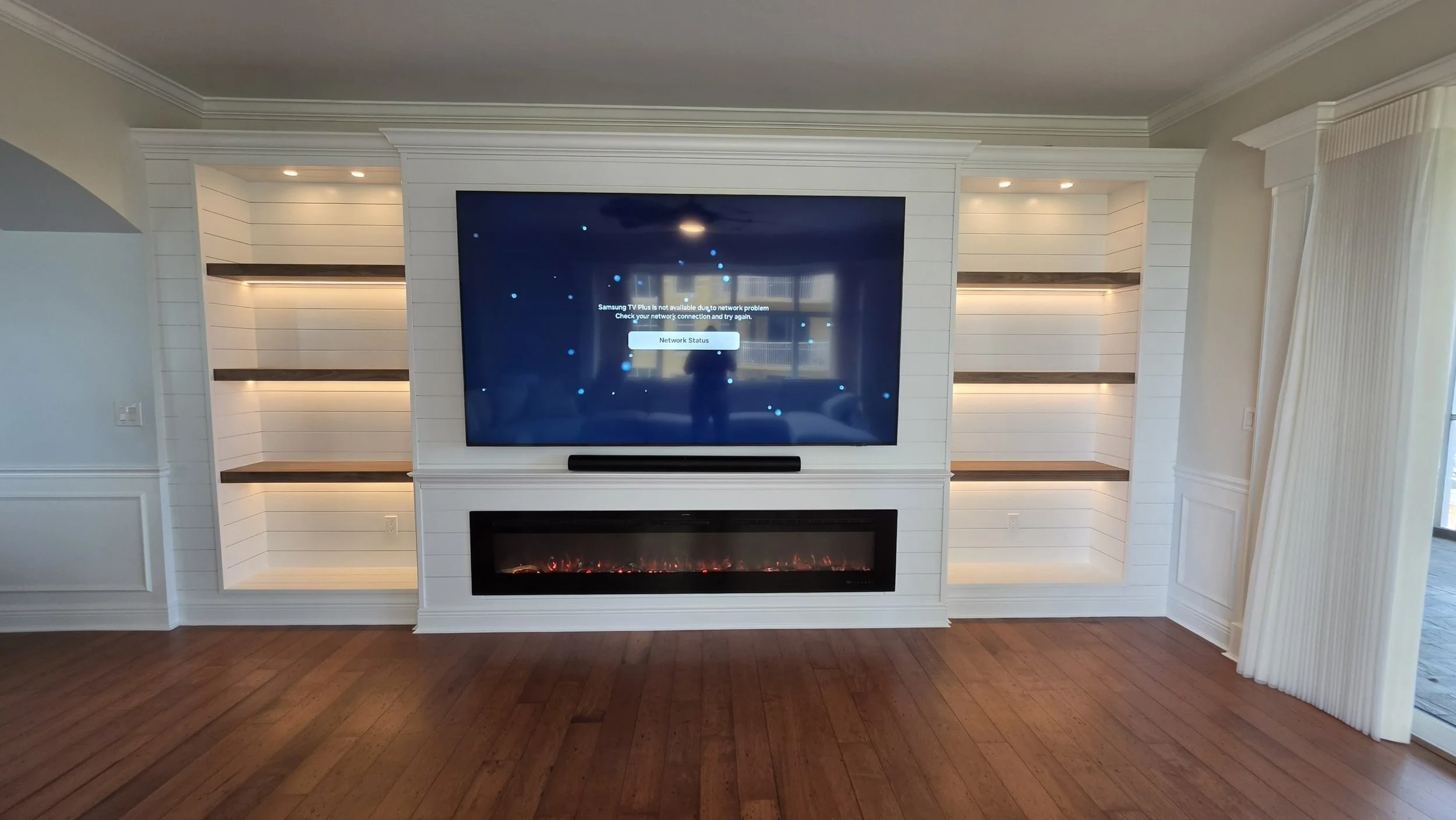Large fireplace media wall with shiplap panels, custom built-in shelving, LED accent lighting and entertainment center in Southwest Florida