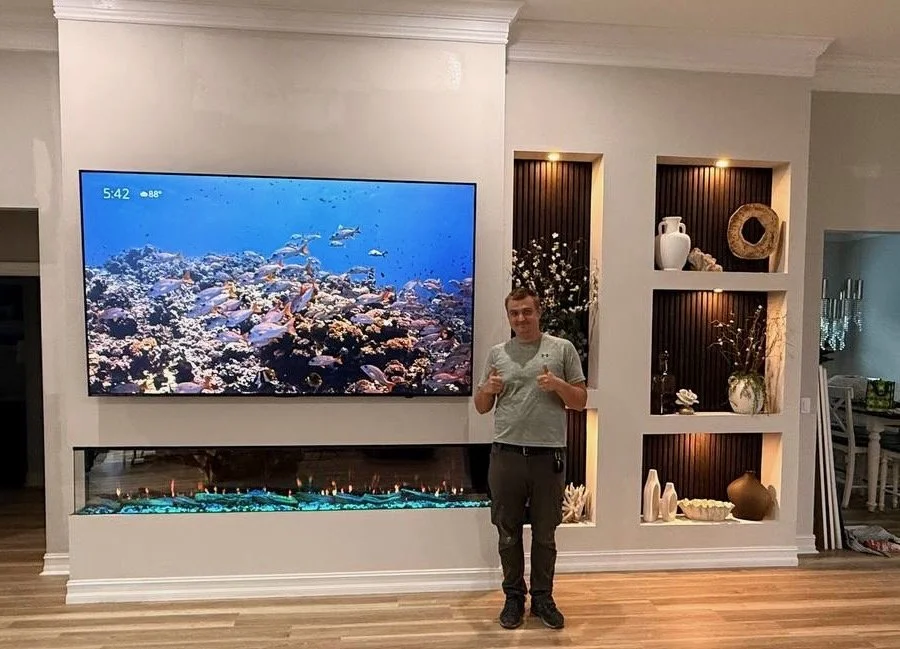 TV Media Wall project specialist standing beside the completed three-sided fireplace media wall with asymmetrical illuminated niches in Melbourne, Florida.