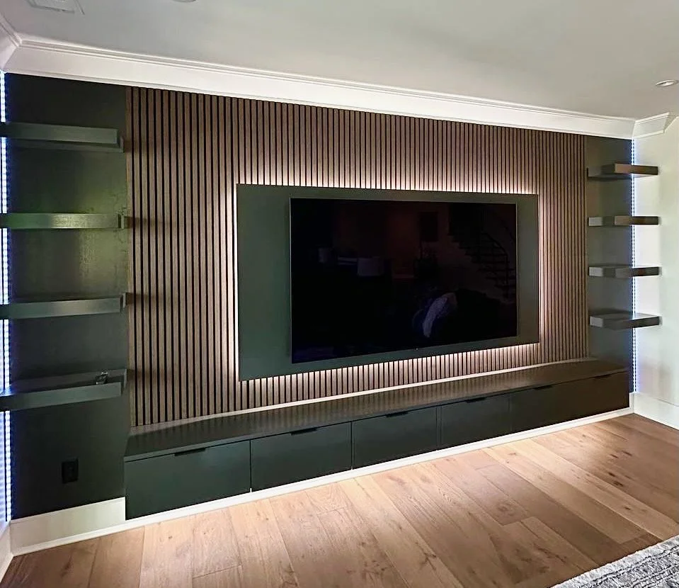 Custom wood slat media wall in Charlotte NC with floating TV panel, LED backlighting, floating cabinet and side shelves