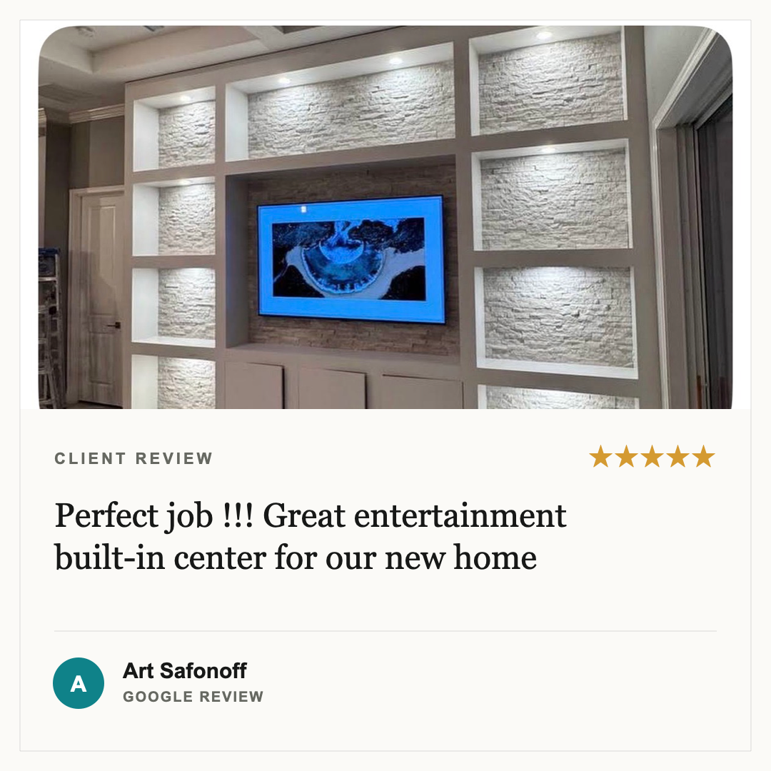 A built-in entertainment center with white shelves and a stone wall behind a mounted TV in a modern living room.