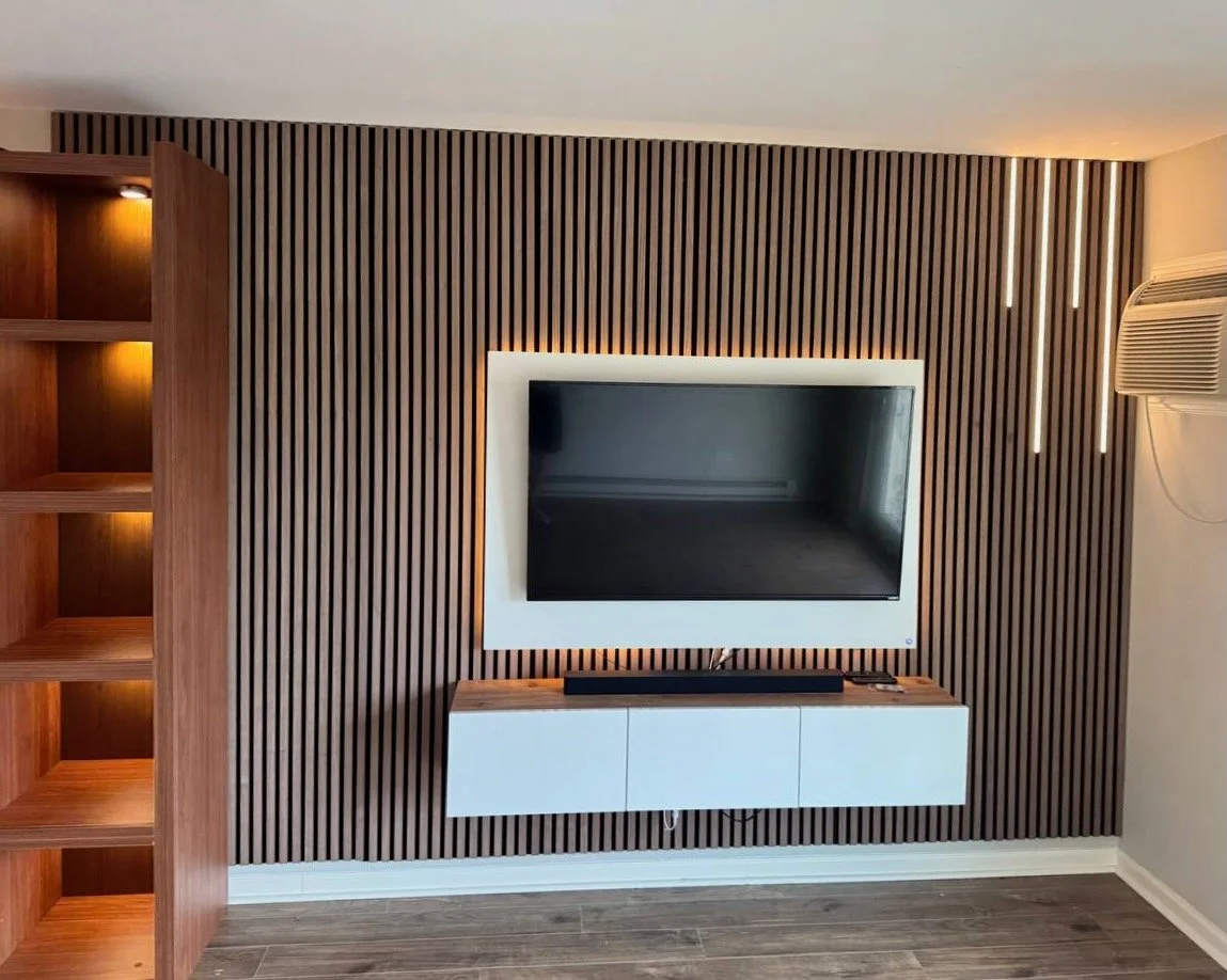Custom white floating cabinet and LED-lit TV panel on vertical wood slat wall in modern Orlando living room.