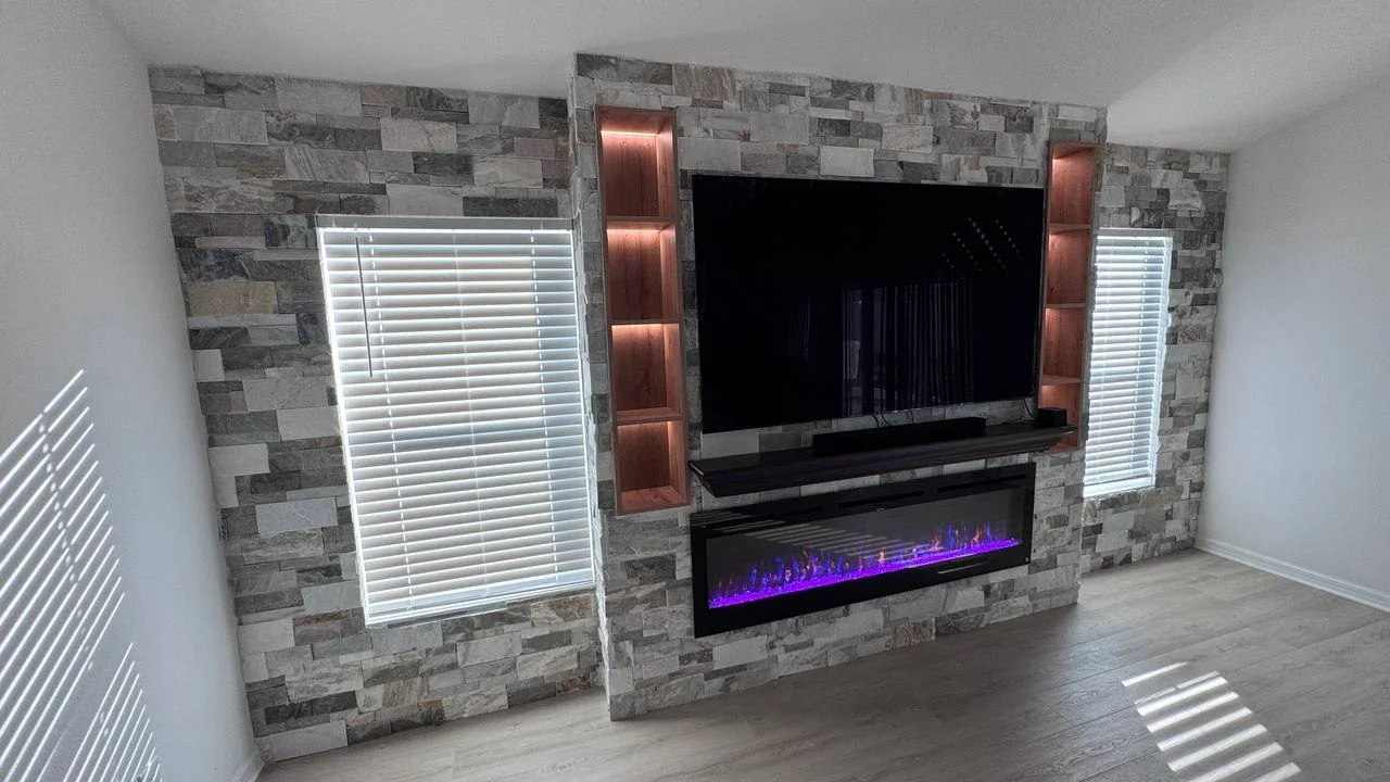 Custom built-out stone TV fireplace wall in Tampa with electric fireplace and integrated vertical niches