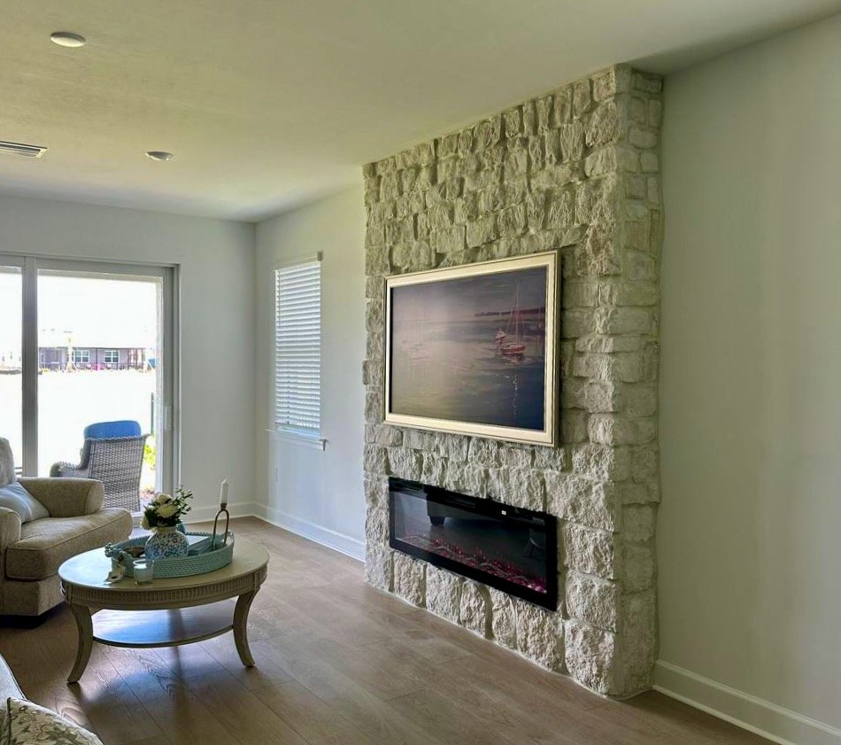 Coastal living room in Punta Gorda featuring a textured white stone fireplace built-out with integrated electric fireplace and artwork.