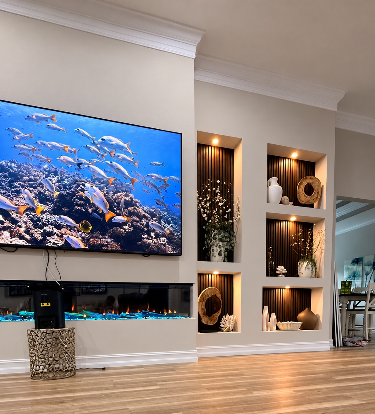 Angled view of a custom Melbourne media wall showing a wide three-sided fireplace and asymmetrical illuminated niches during the final setup stage