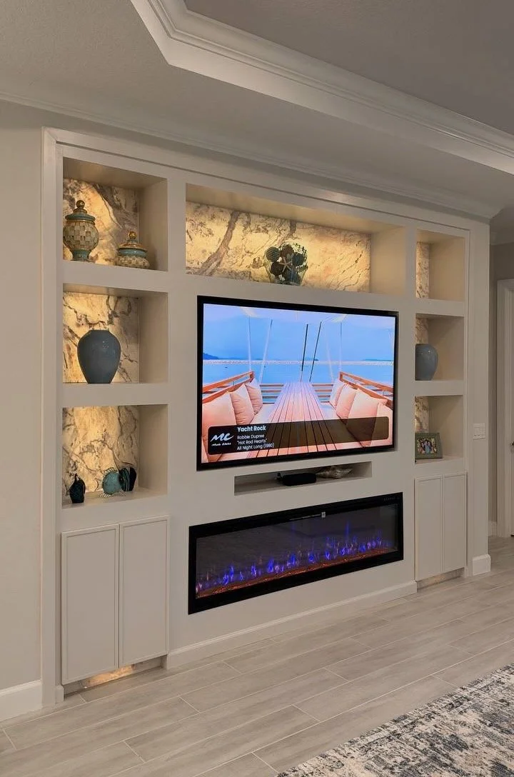 Completed C-Series Modern Niche Media Wall with warm backlighting, lower storage cabinets, TV, and linear fireplace.