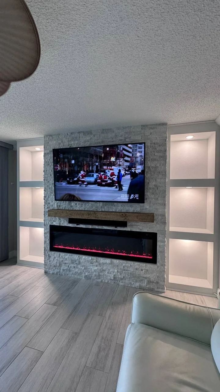 Angled view showing the depth of the stone center section, linear fireplace, and recessed niches with spotlighting on both sides.