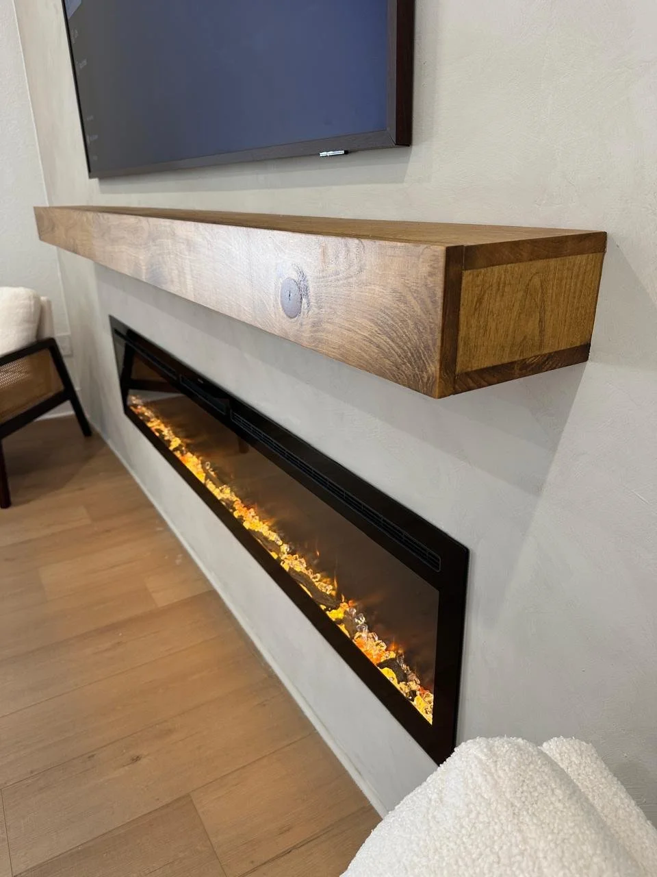 custom floating wood mantel detail above linear electric fireplace