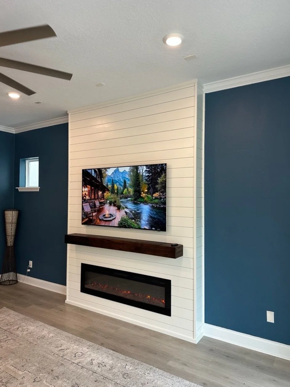 Shiplap fireplace media wall with custom stained wood mantel and linear electric fireplace in Orlando home.
