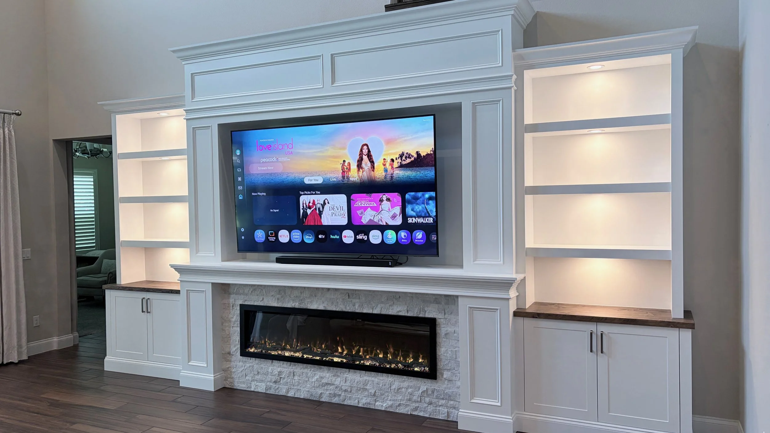 Classic built-in entertainment wall featuring custom millwork, crown molding, LED shelves and linear electric fireplace