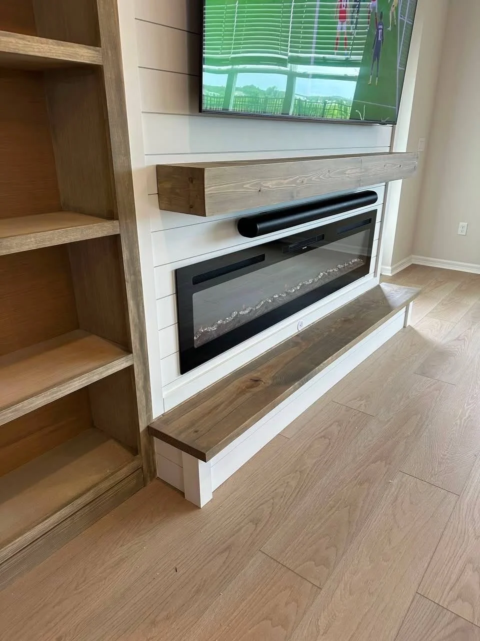 Close-up view of a modern electric fireplace, floating mantel, and shiplap media wall detail