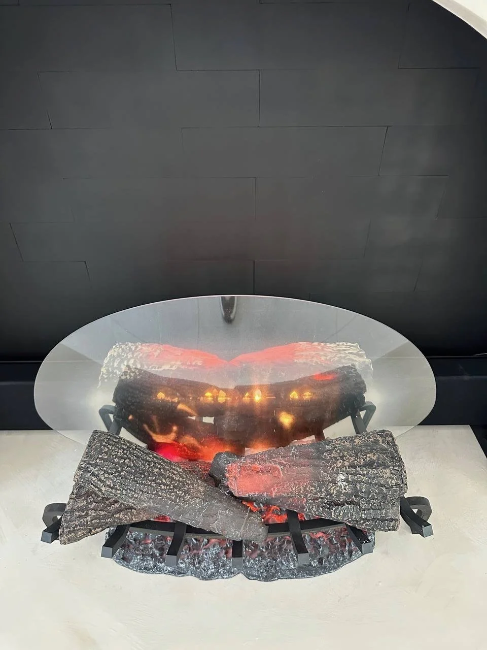 Close view of an electric log fireplace installed inside a black arched firebox on a custom Mediterranean Hearth Wall