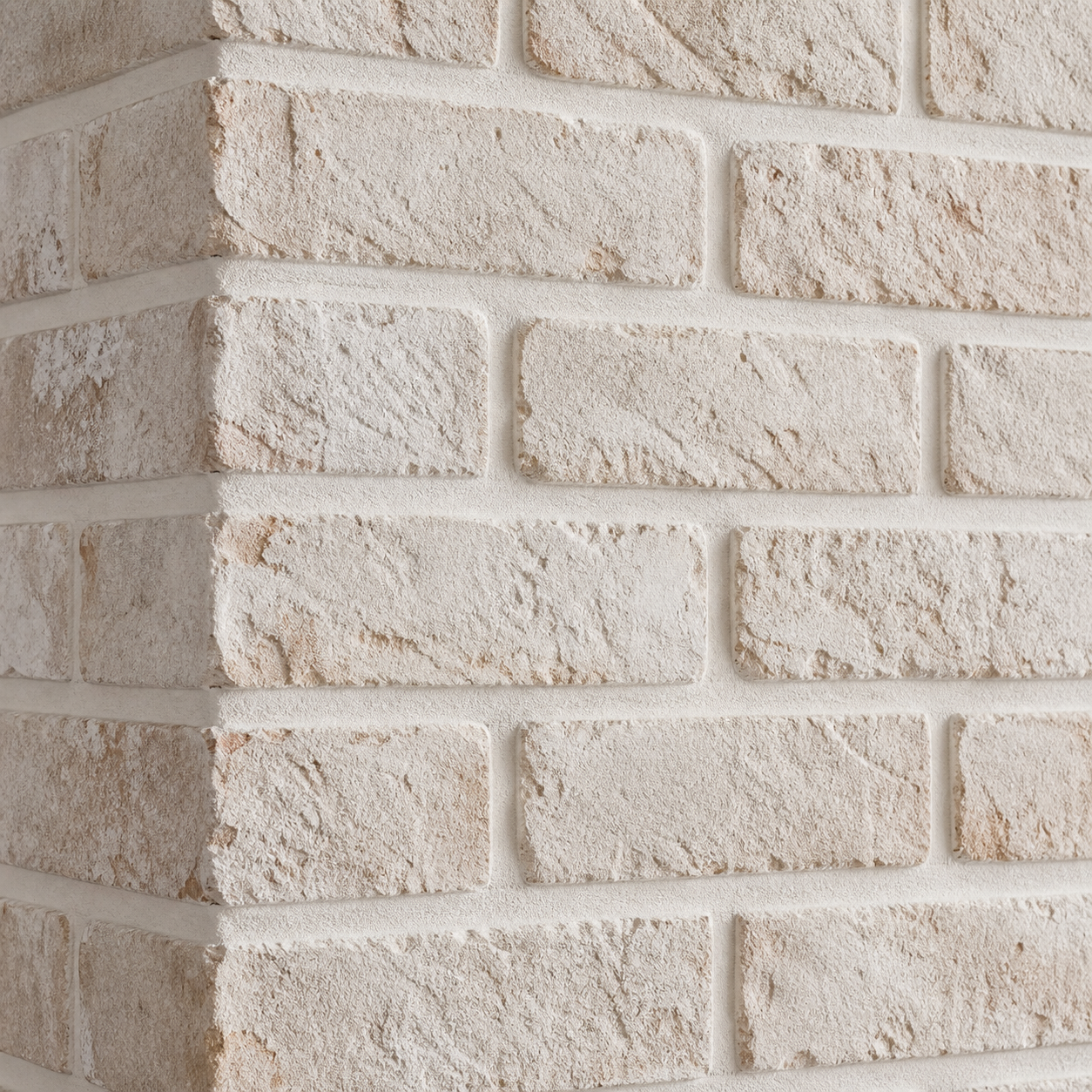Close-up of warm-white limewashed brick in a staggered running-bond pattern with textured faces and light mortar joints