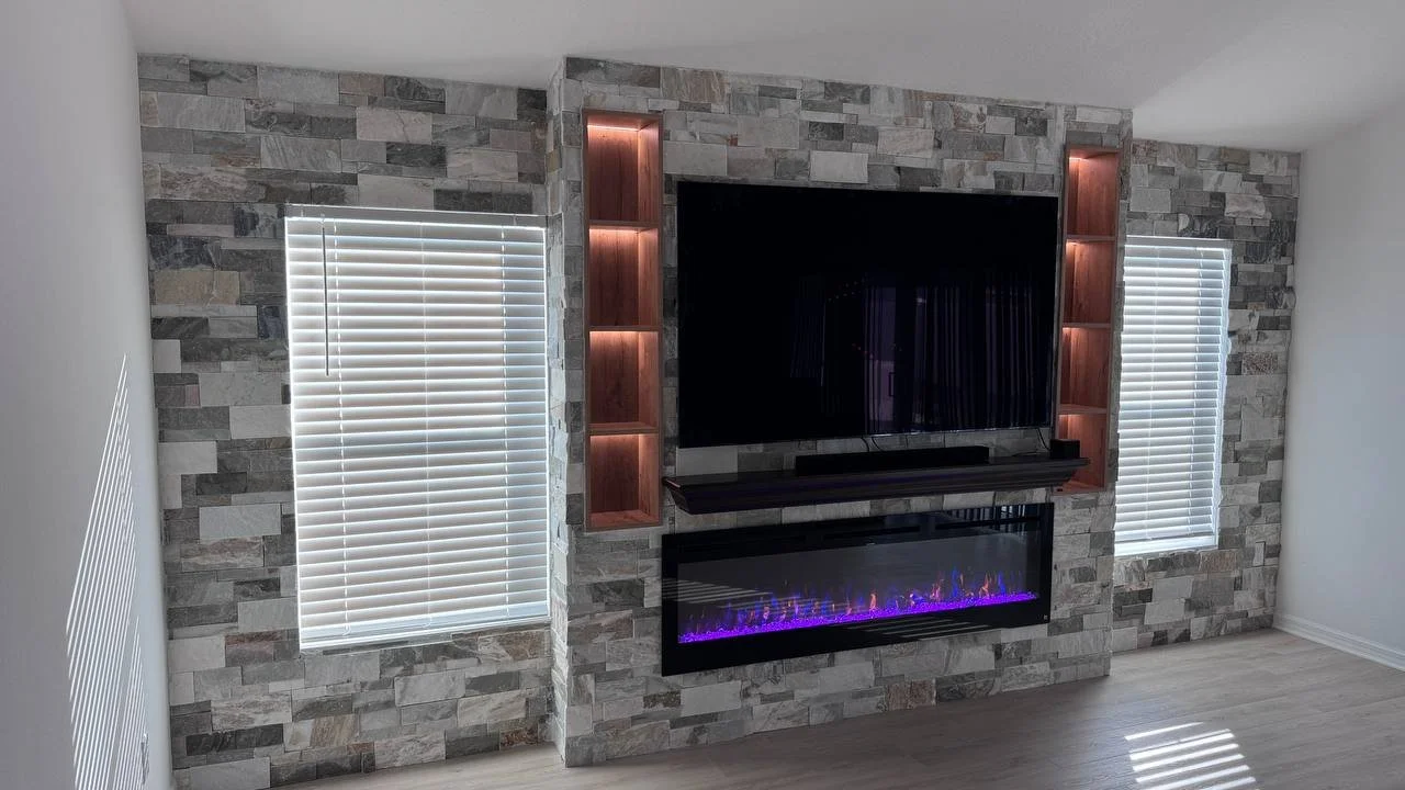 Tampa fireplace entertainment wall with stacked stone finish, large TV and warm LED display niches