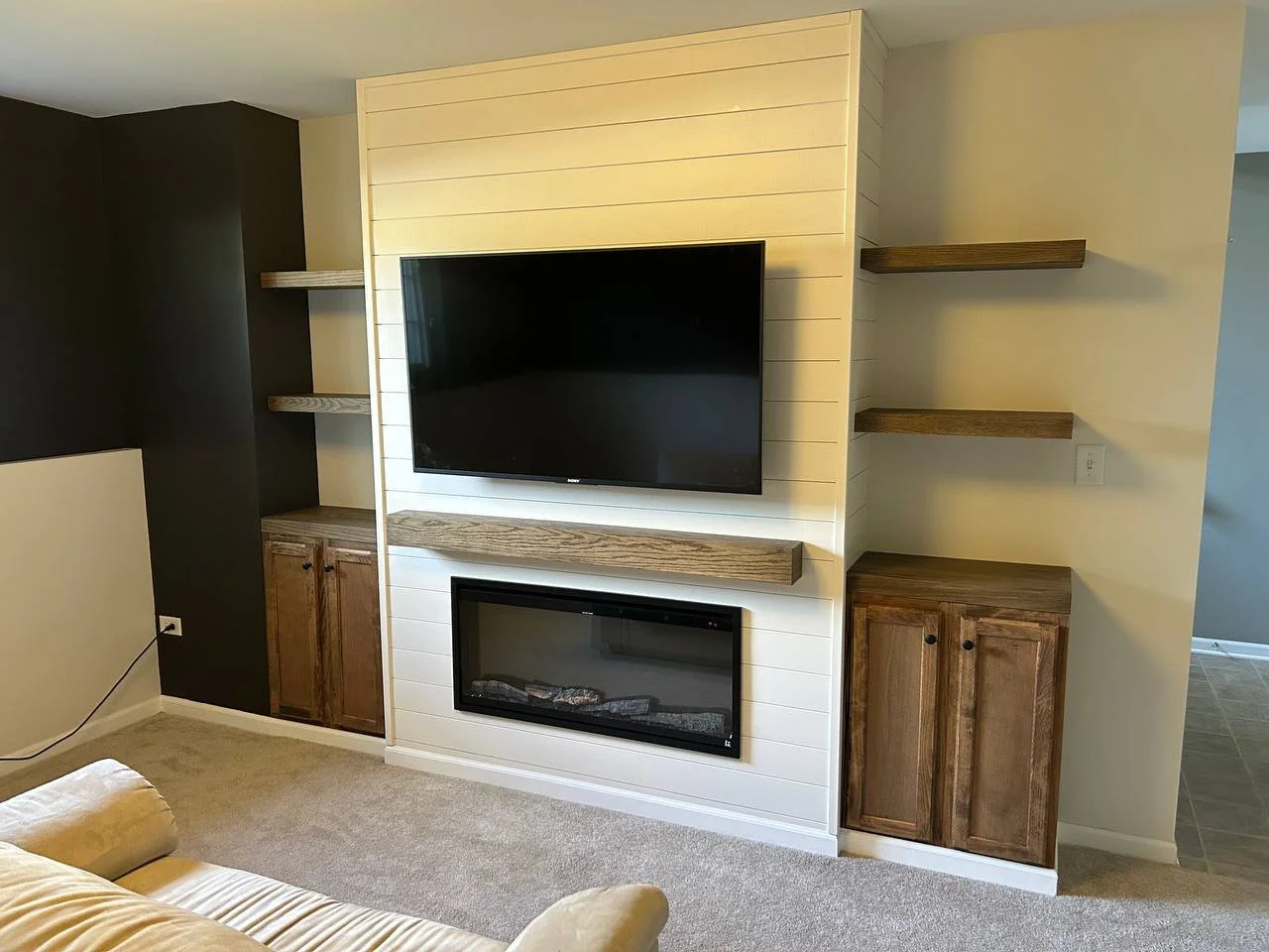 Custom entertainment wall with white shiplap, electric fireplace, mounted TV, and wood cabinetry in Seminole County home.