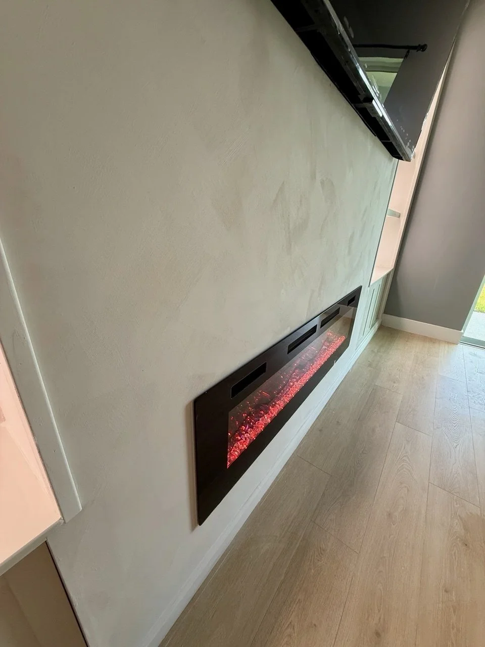 Electric fireplace integrated into limewash TV media wall in Bradenton Sarasota Area