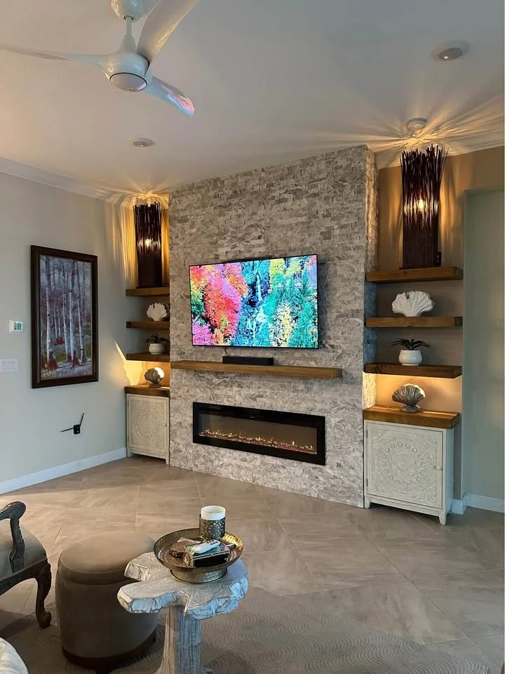 ledger stone TV media wall with electric fireplace floating shelves and decorative lighting in Southwest Florida home