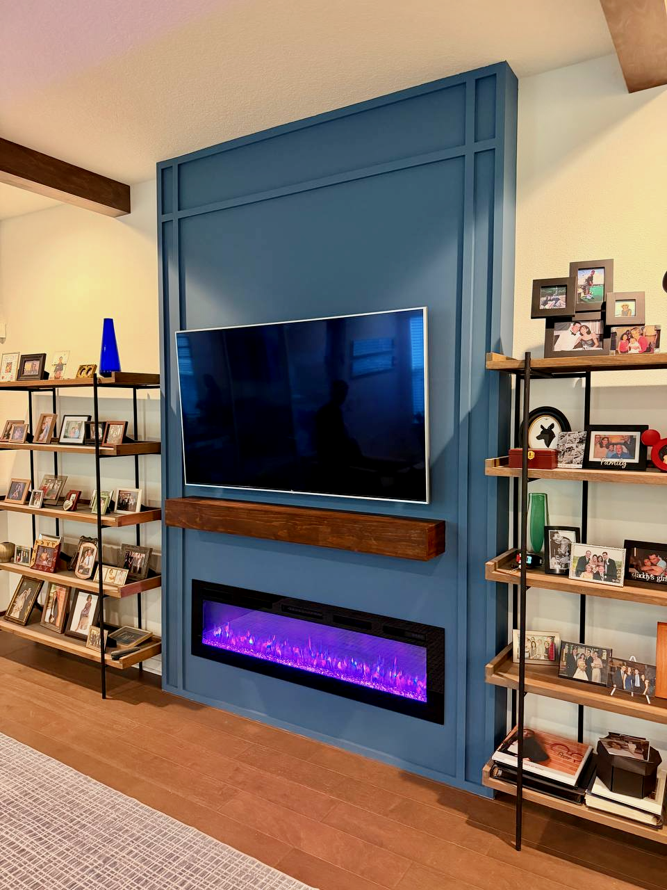Floor to ceiling blue media wall with electric fireplace and mounted TV in Florida living room