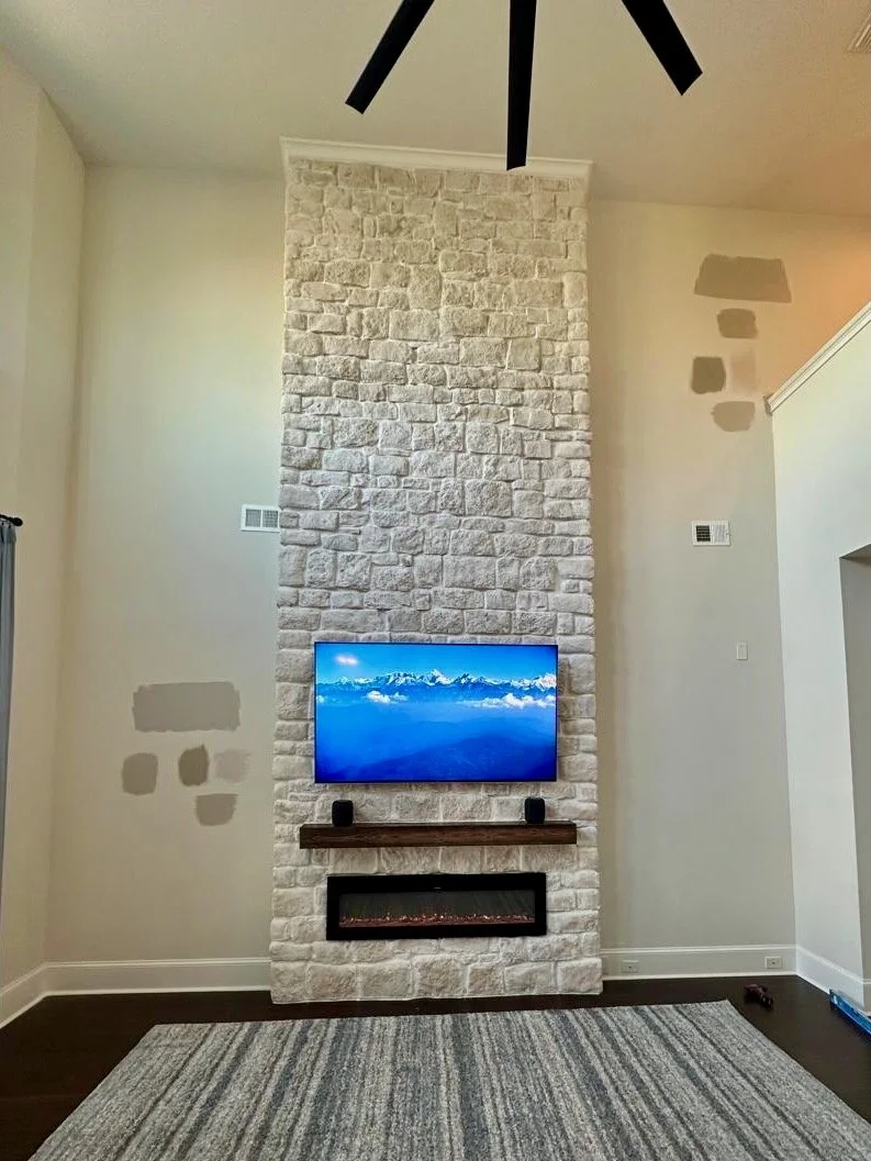floor to ceiling stone fireplace media wall with mounted TV and electric fireplace in Orlando living room