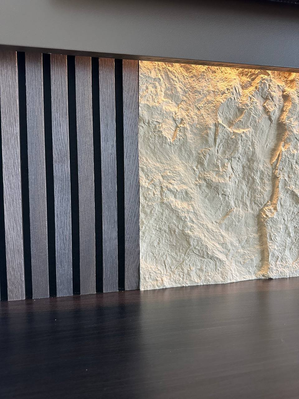 Close-up of textured stone wall panel and wood slat accent media wall