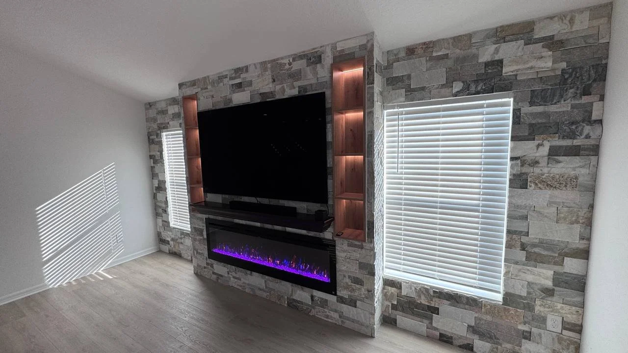 Full-width stacked stone media wall in Tampa wrapping around windows with TV, fireplace and illuminated niches