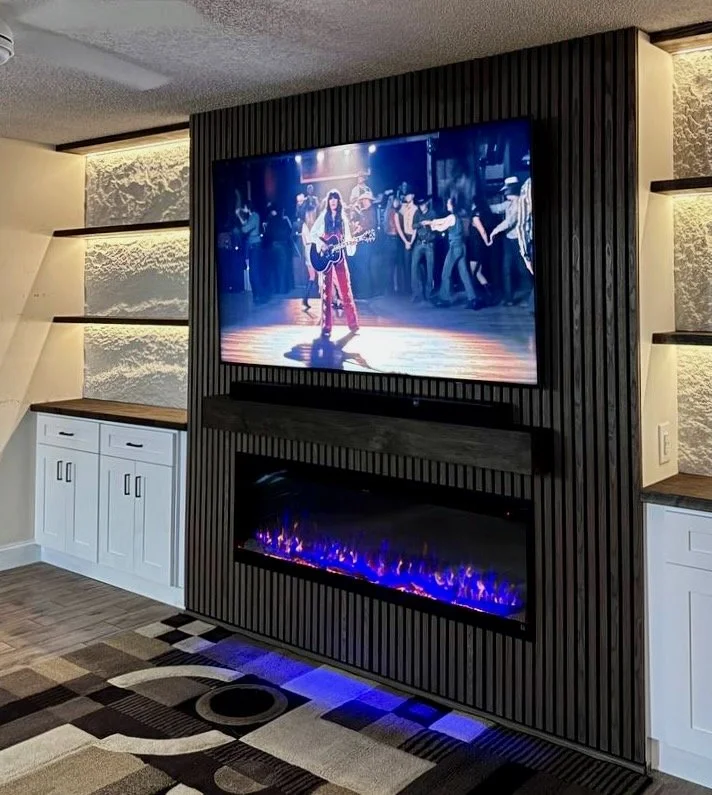 Built-in entertainment center in the Tampa area with vertical slats, an electric fireplace, white shaker cabinets, wood countertops, and LED-lit niches.