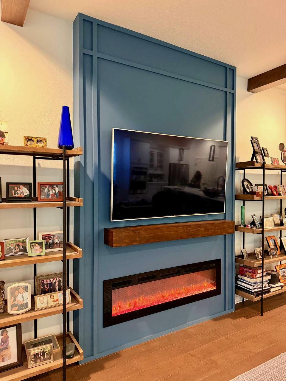 Custom TV fireplace wall with blue accent finish and stained wood mantel in Orlando area home